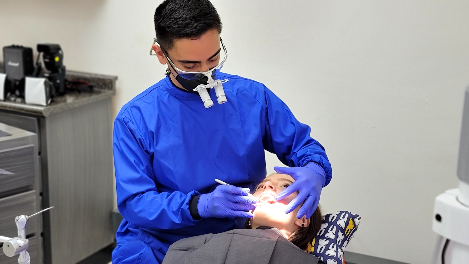 Dr. Francisco cleaning patients teeth.